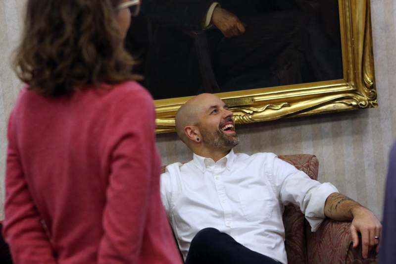 a man sitting on a couch with a woman in the background