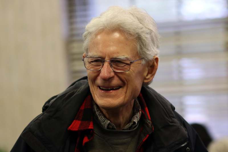 a man with white hair and glasses smiling