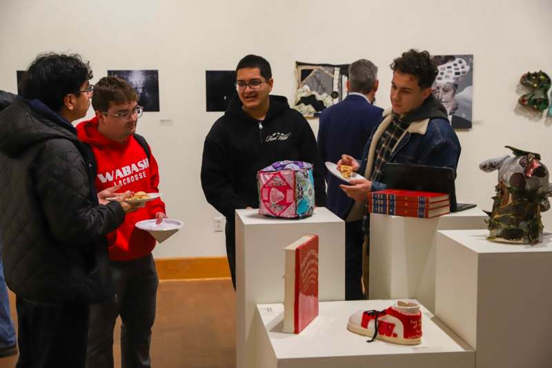 a group of people standing around a table with food and books