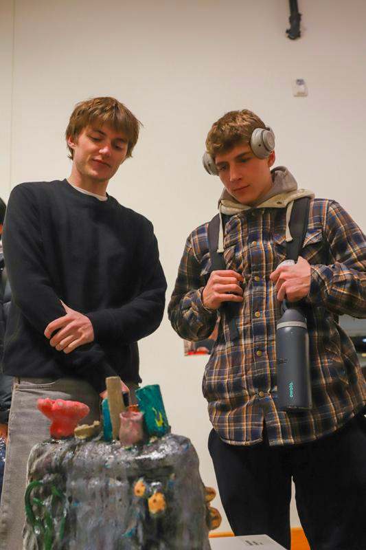 two men standing next to a sculpture
