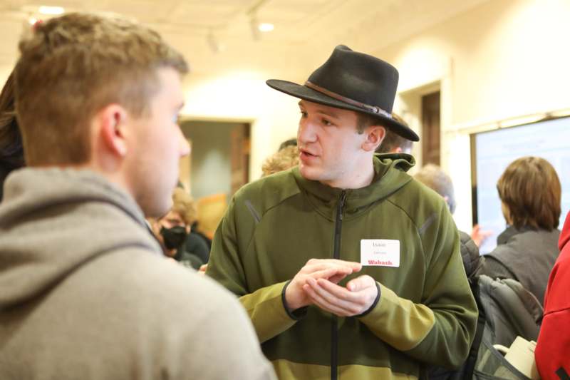 a man wearing a hat talking to another man