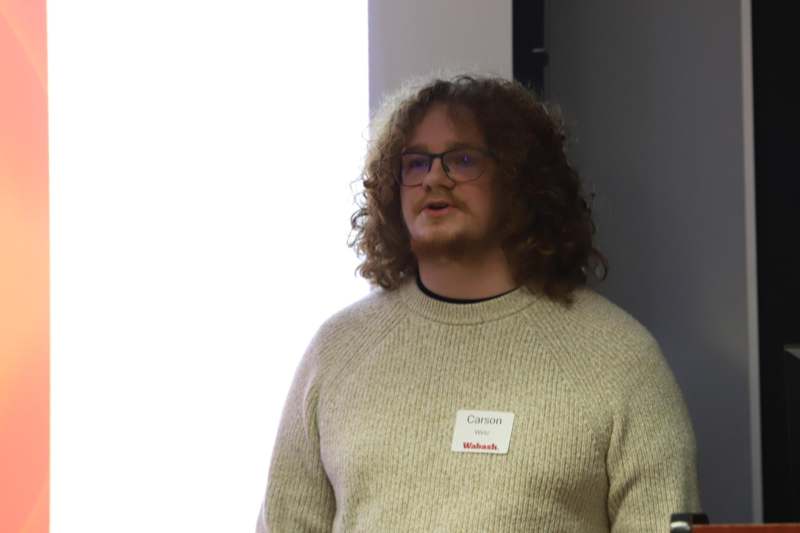 a man with long curly hair wearing a name tag