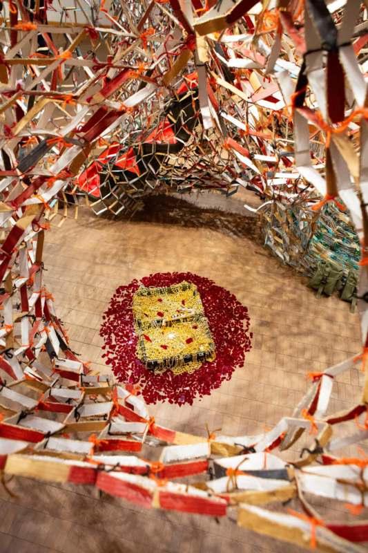a room with many pieces of paper and a gold square with red and white ribbons