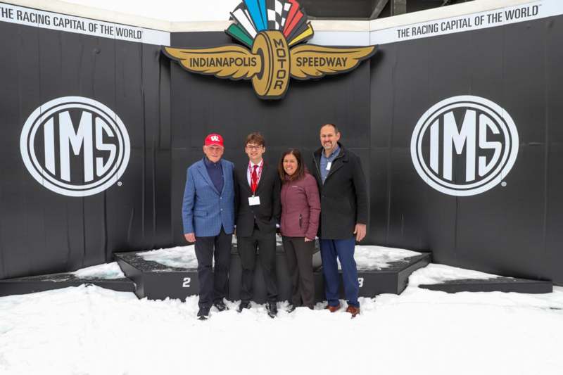 a group of people standing in front of a black wall with white logo