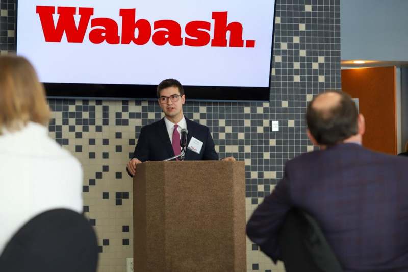 a man standing at a podium with a microphone and a screen behind him