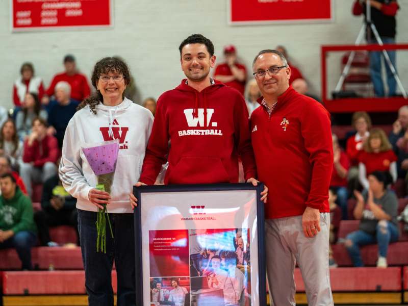 a group of people standing in a gym holding a framed picture