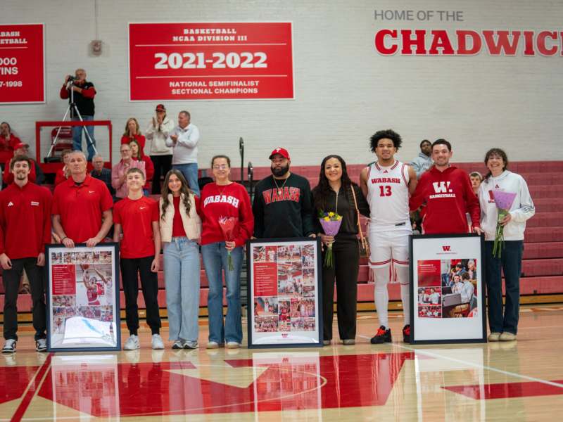 a group of people standing in a gym holding framed pictures