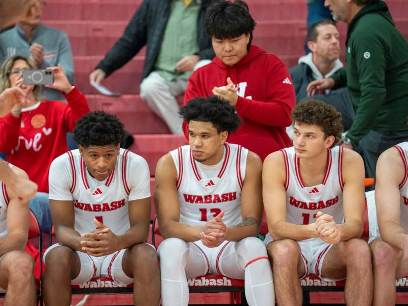 a group of men sitting on bench in a stadium