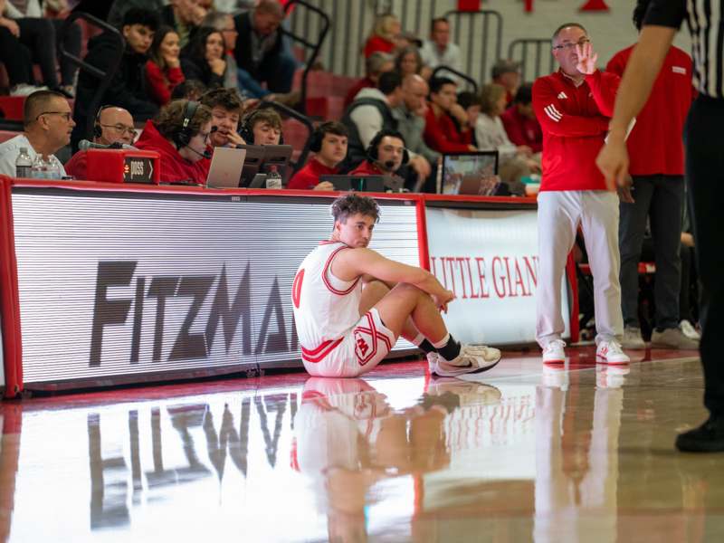 a man sitting on the floor of a basketball court