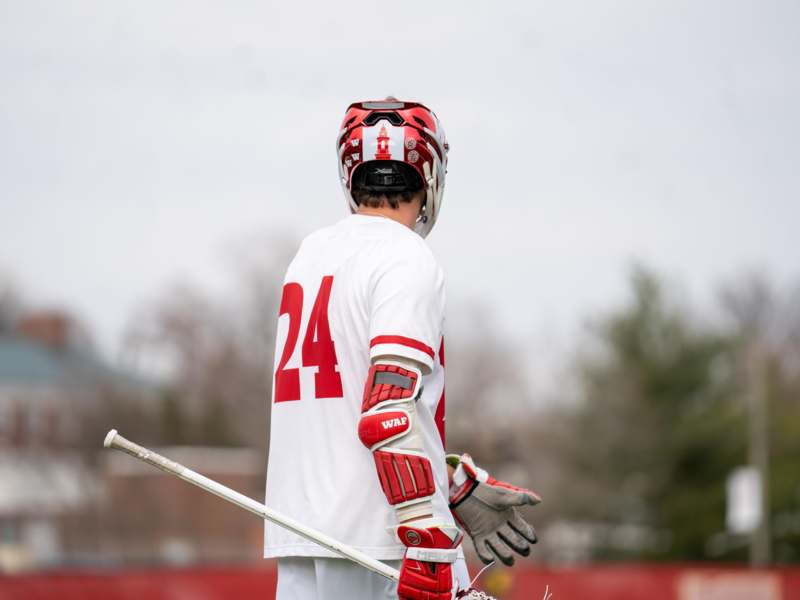 a person wearing a helmet and gloves holding a lacrosse stick
