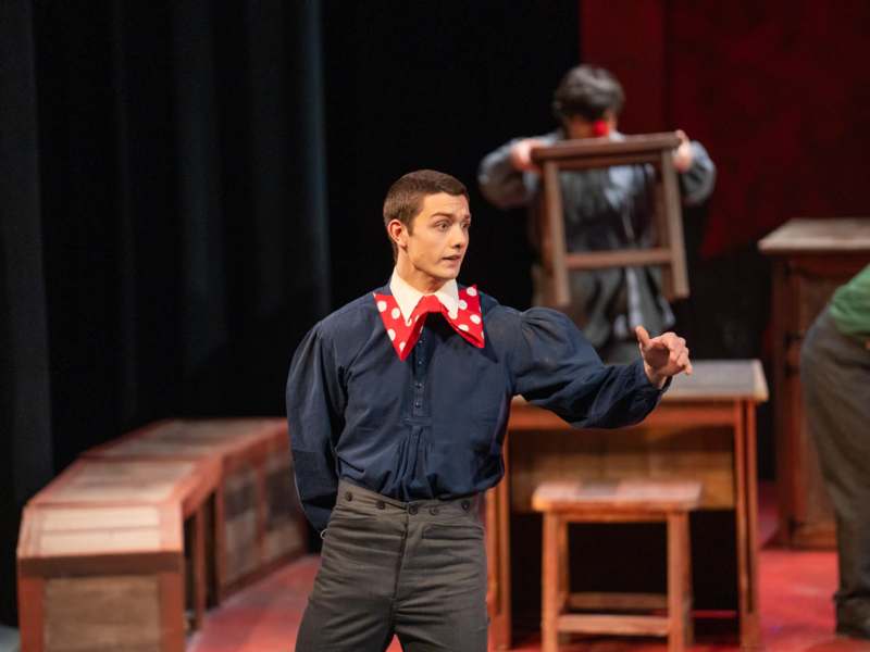 a man in a blue shirt and red polka dot bow tie