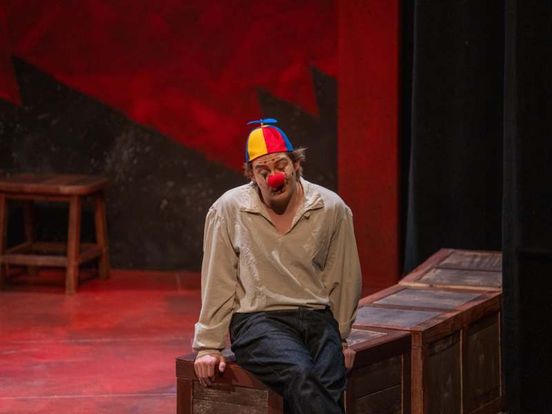 a man wearing a clown hat sitting on a wooden box