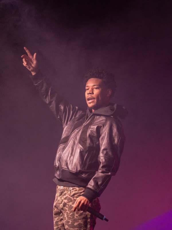 a man in a leather jacket holding his hand up