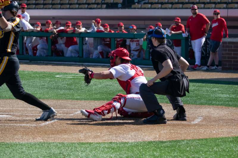 a baseball player in a red uniform and a catcher in a red helmet