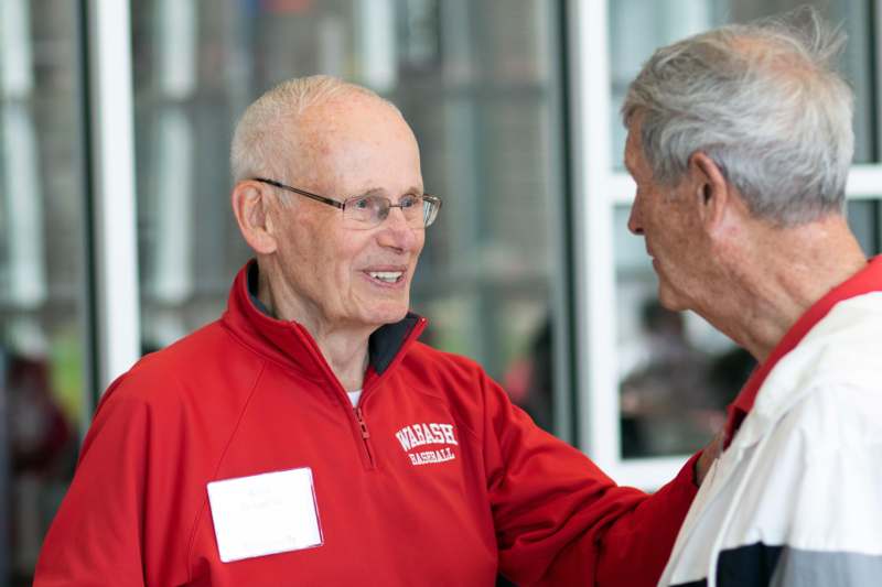 a man in a red jacket talking to another man
