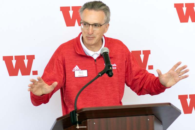a man standing at a podium with his hands out