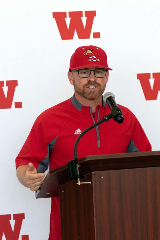 a man wearing a red hat and standing at a podium
