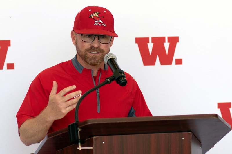 a man in red shirt and hat speaking into a microphone