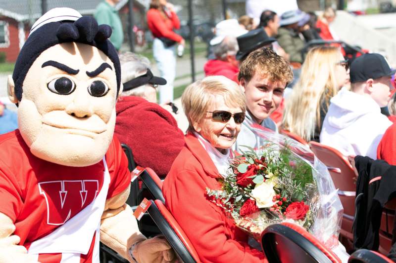 a group of people sitting in chairs with a mascot and flowers