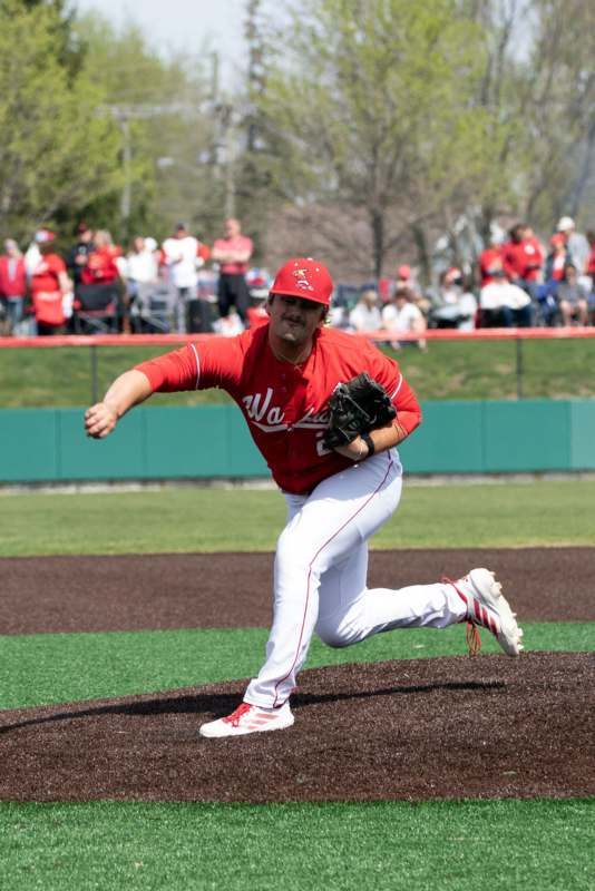 a baseball player in a red uniform throwing a baseball