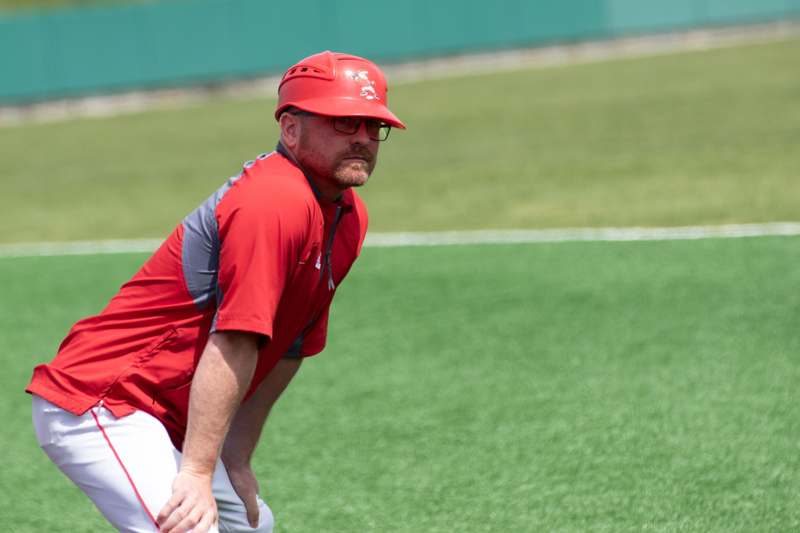 a man in a red shirt and helmet on a baseball field