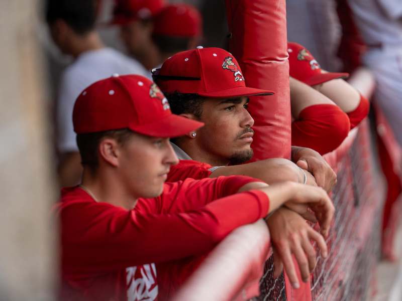 a group of men in red hats leaning against a fence