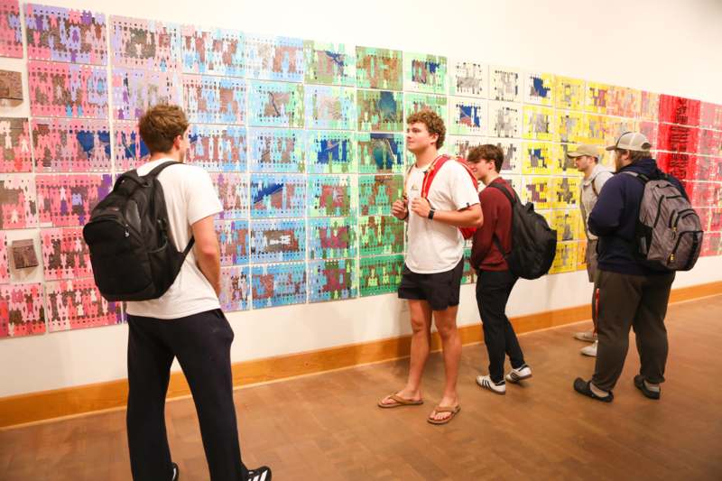 a group of people looking at a wall with many pieces of puzzle