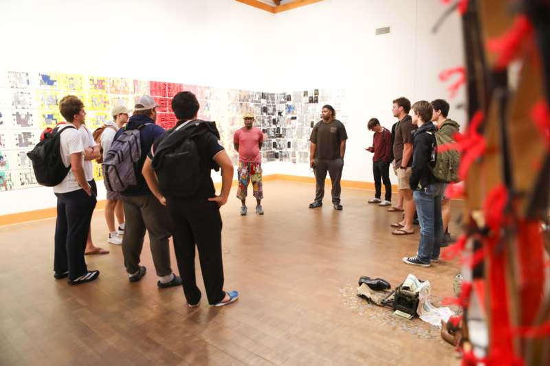 a group of people standing in a room with a wall of pictures