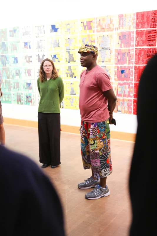 a man in colorful shorts and a woman in front of a wall with many posters