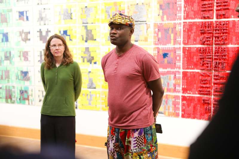 a man in a red shirt and colorful hat standing in front of a woman