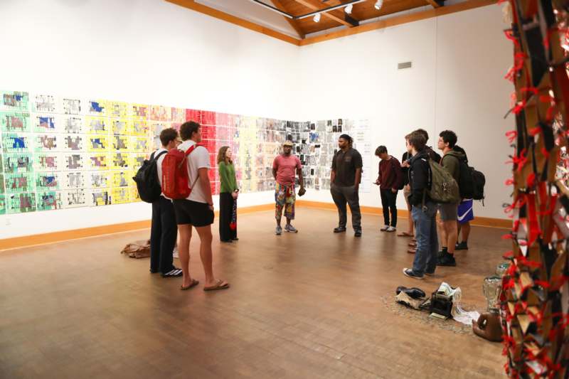 a group of people in a room with a wall of pictures