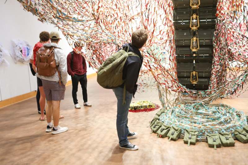 a group of people looking at a wall covered in ribbons
