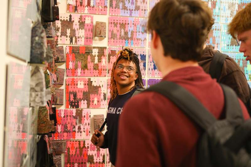 a man looking at a wall of colorful paper