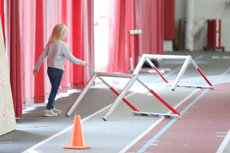 a girl walking on a track with a barrier
