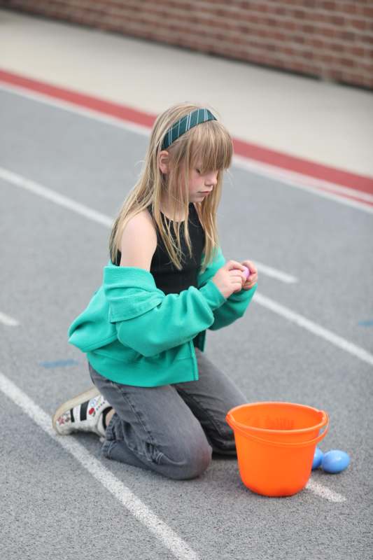 a girl kneeling on the ground with a bucket and a bucket