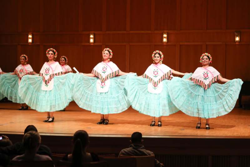 a group of women wearing dresses and standing on a stage