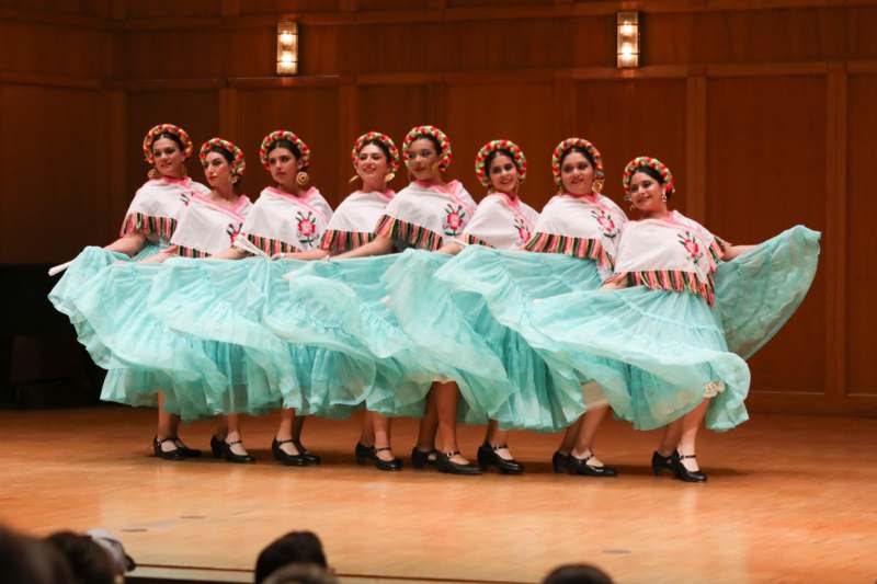a group of women wearing dresses and standing on a stage