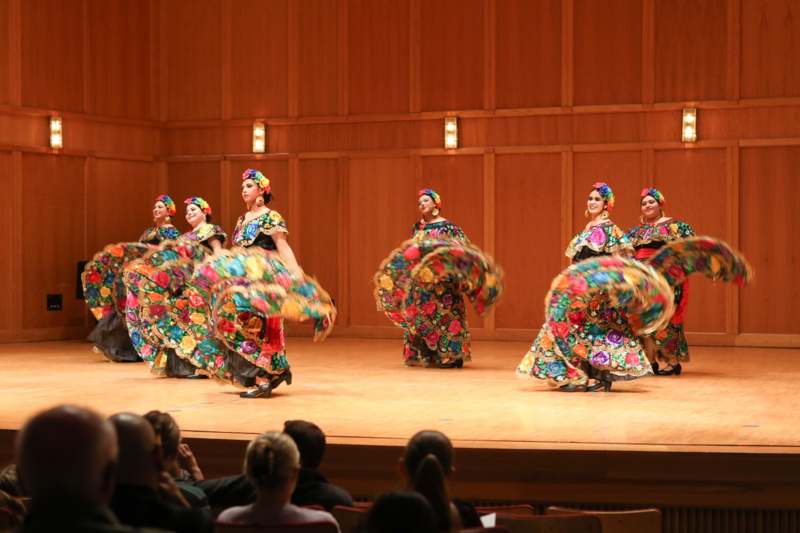 a group of women wearing colorful dresses on a stage
