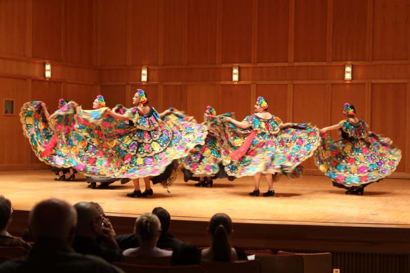 a group of women wearing colorful dresses on a stage