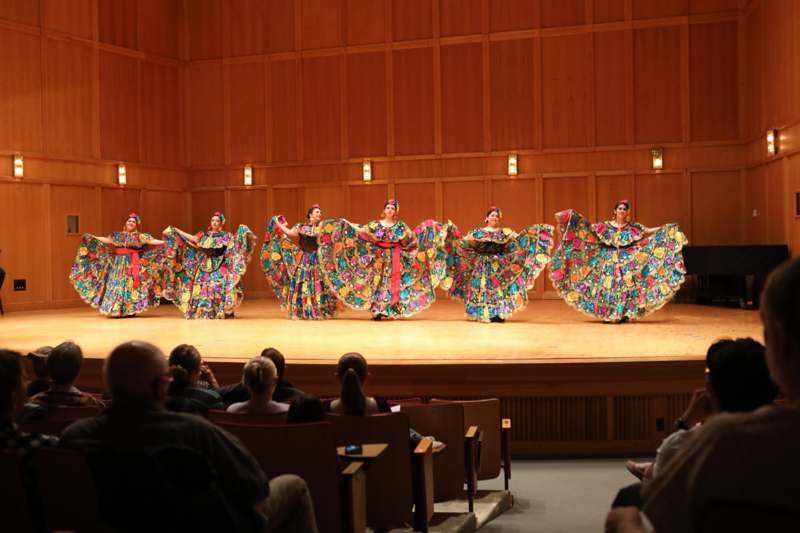 a group of women in colorful dresses on a stage