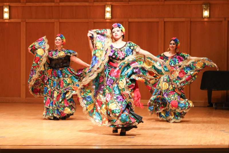 a group of women wearing colorful dresses on a stage