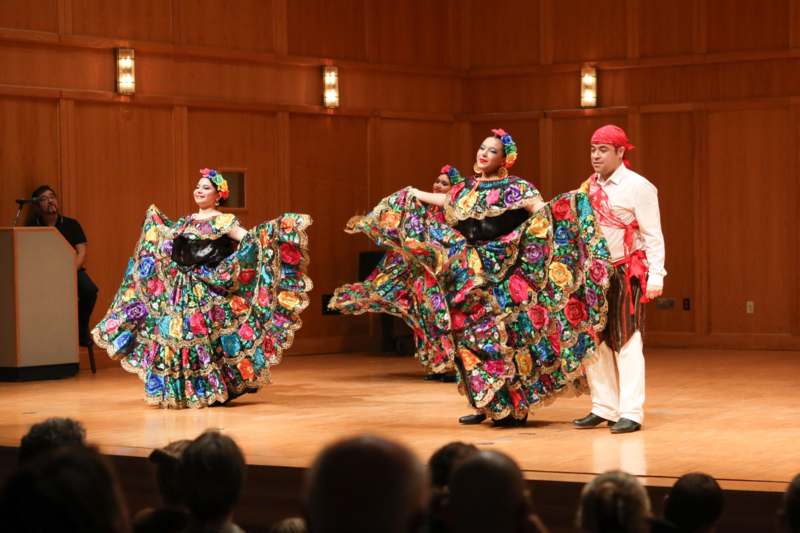 a group of people wearing colorful dresses on a stage