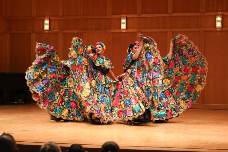 a group of women wearing colorful dresses on a stage