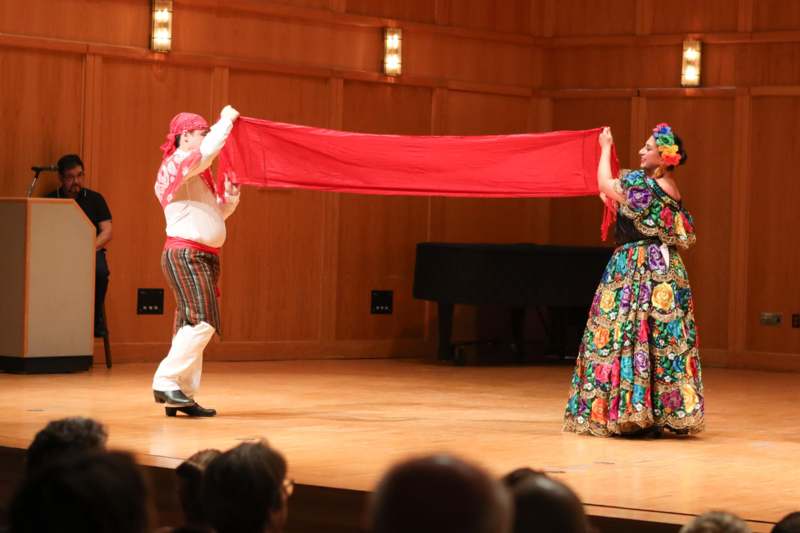 a man and woman on a stage holding a red scarf