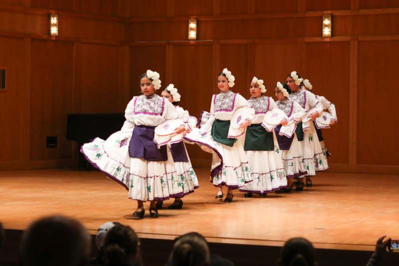 a group of women in white and purple dresses on a stage