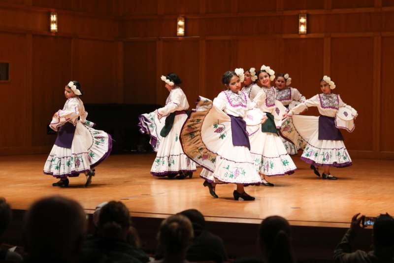a group of women in white dresses dancing on a stage