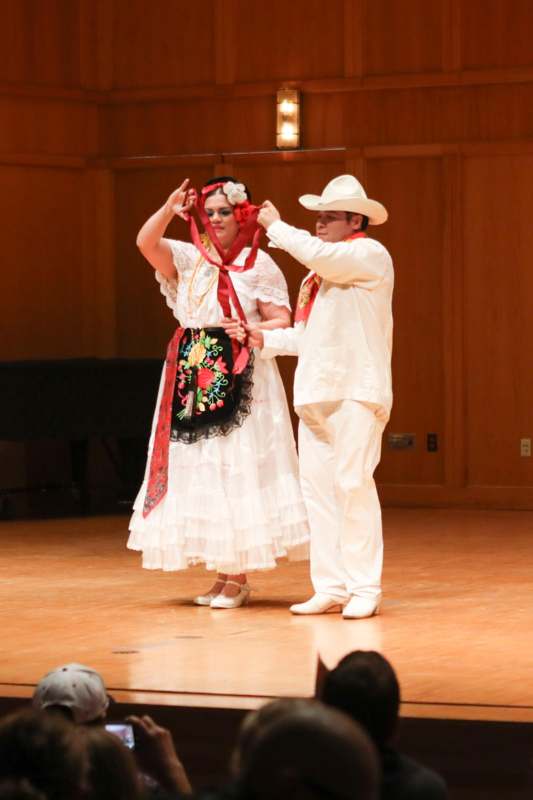 a man and woman wearing white clothes and a red scarf