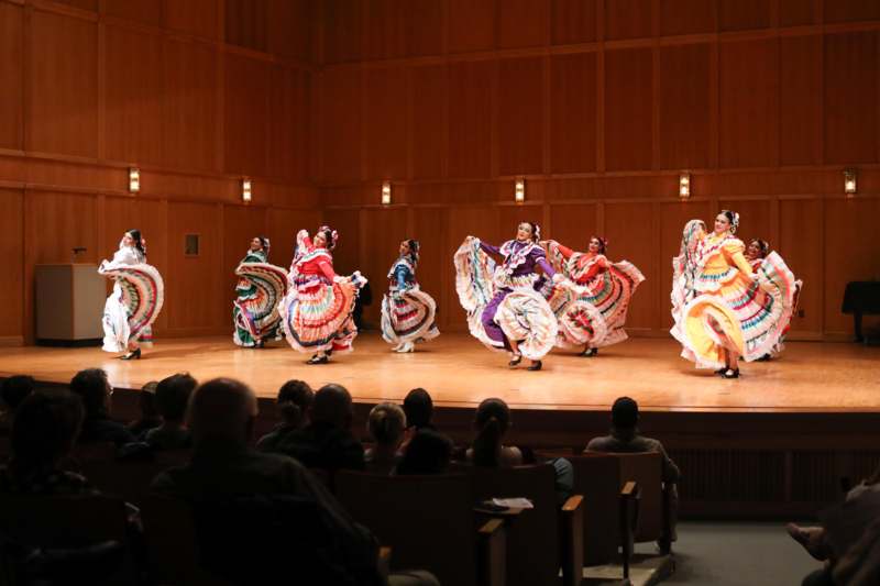 a group of women in colorful dresses on a stage