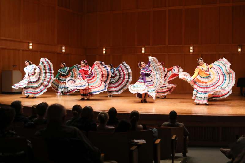 a group of women in colorful dresses on a stage