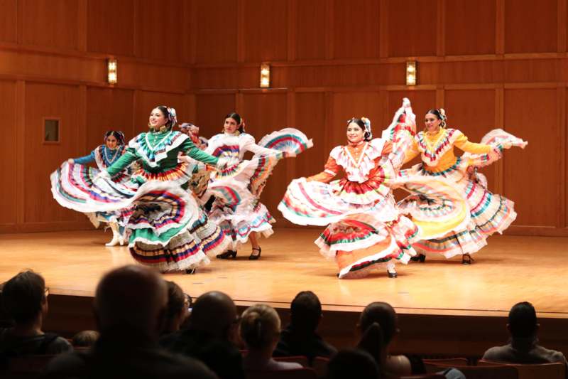 a group of women in colorful dresses on a stage